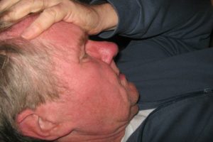 Mann mit Kopfschmerzen hält sich den Kopf