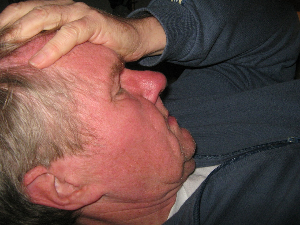 Mann mit Kopfschmerzen hält sich den Kopf